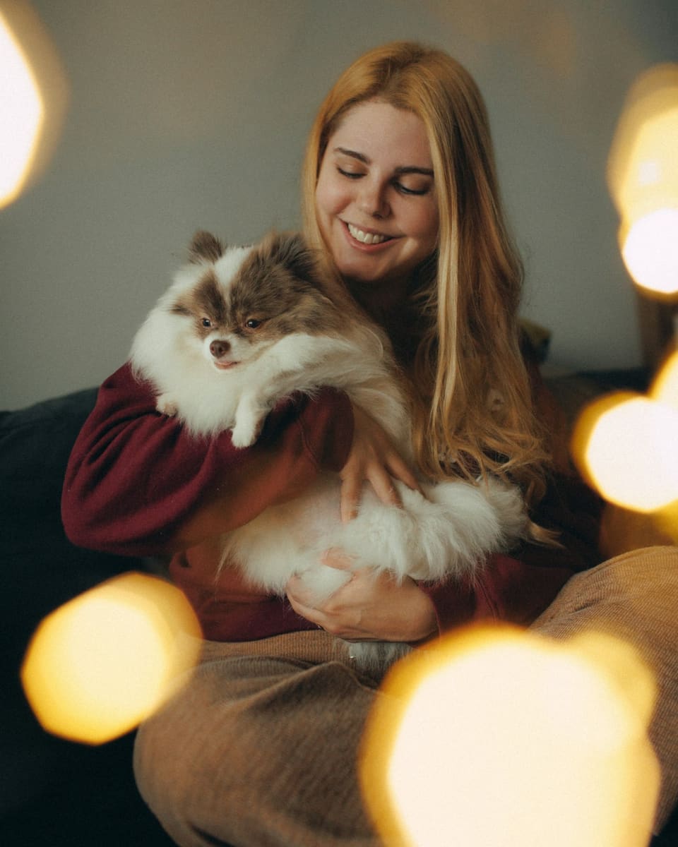 Una persona accarezza il proprio cane sul divano di casa, in una luce calda